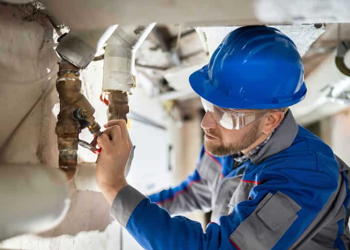 Expert in blue hard hat handling water pipe repair Overland Park, Kansas.